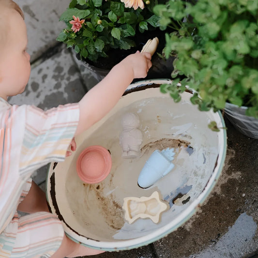 Ein kind hält eine beige, leicht beschädigte keramikschale mit badespielzeug space schimmelresistent und bunten
