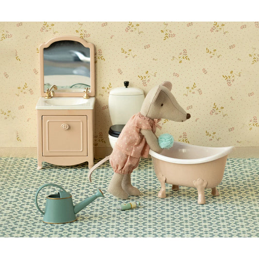 Eine beige mauspuppe in einem rosa gepunkteten kleid steht neben einer pastell pfirsich badewanne geschenke für neugeborene