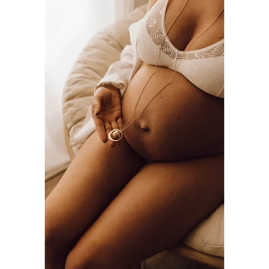 Schwangere Frau mit Ring berührt ihren Bauch, GAÏA Schwangerschaftsbola in Roségold