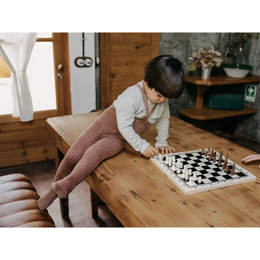 Kind spielt Schach auf einem Holztisch mit Granny Teddy Fußstrumpfhosen von Granola