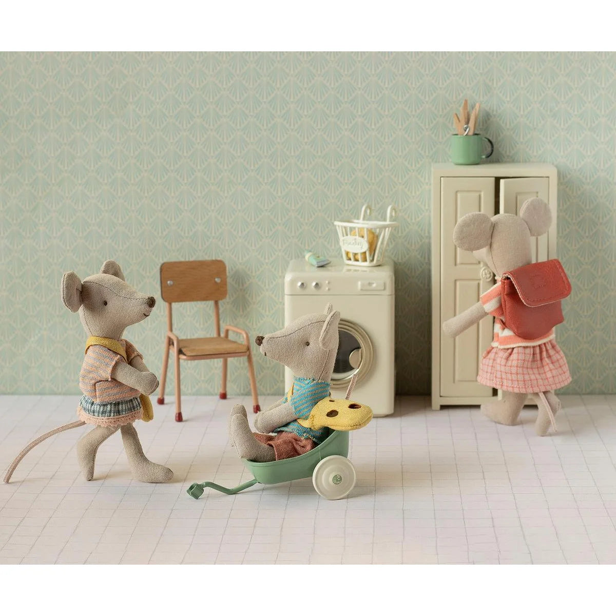 Eine weiche beige mausfigur mit blauem pullover und brauner hose sitzt in einem mintgrünen spielzeugwagen kleine schwester