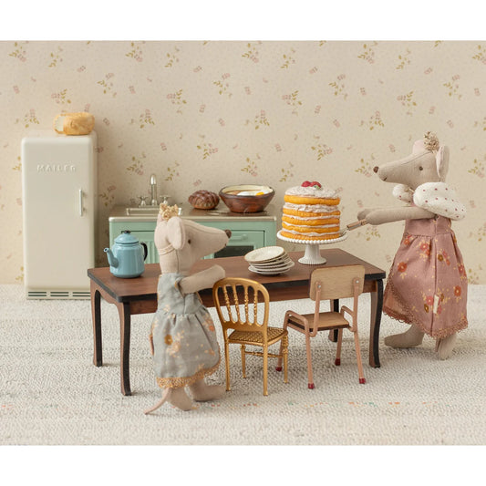 Langer esstisch maus mit mehrstöckigem gelben kuchen mit weißer glasur und roten beeren geschenke für neugeborene