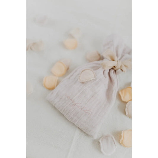Ein zarter offwhite muslin konfetti beutel mit rosa stickerei und gerafftem top für ökologische baby- und kinderprodukte