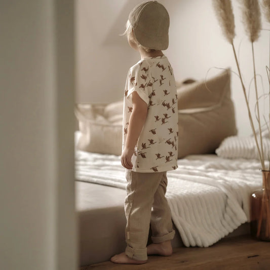 Kind in passendem beigen Outfit mit Musselinhose lang in beige