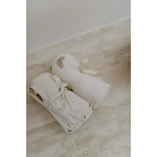 Zwei gerollte off-white muselintücher 70x70 cm mit herz- und blattmustern, nachhaltige babykleidung schweiz