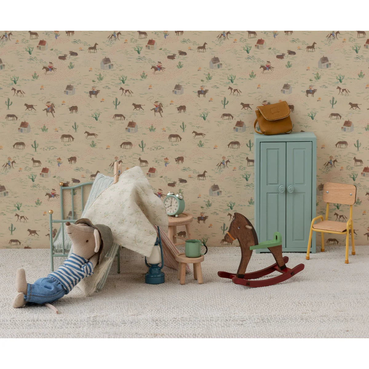 Miniaturer Cowboy-Maus im Schlafzimmer mit Schaukelpferd in Dunkelbraun