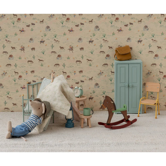 Miniaturer Cowboy-Maus im Schlafzimmer mit Schaukelpferd in Dunkelbraun