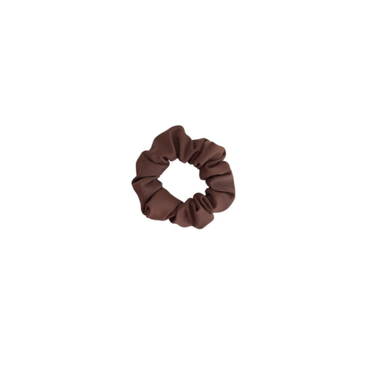 Ein mini scrunchie aus weichem schokoladenbraunem stoff mit elastischer, geraffter textur von mini + me mocha