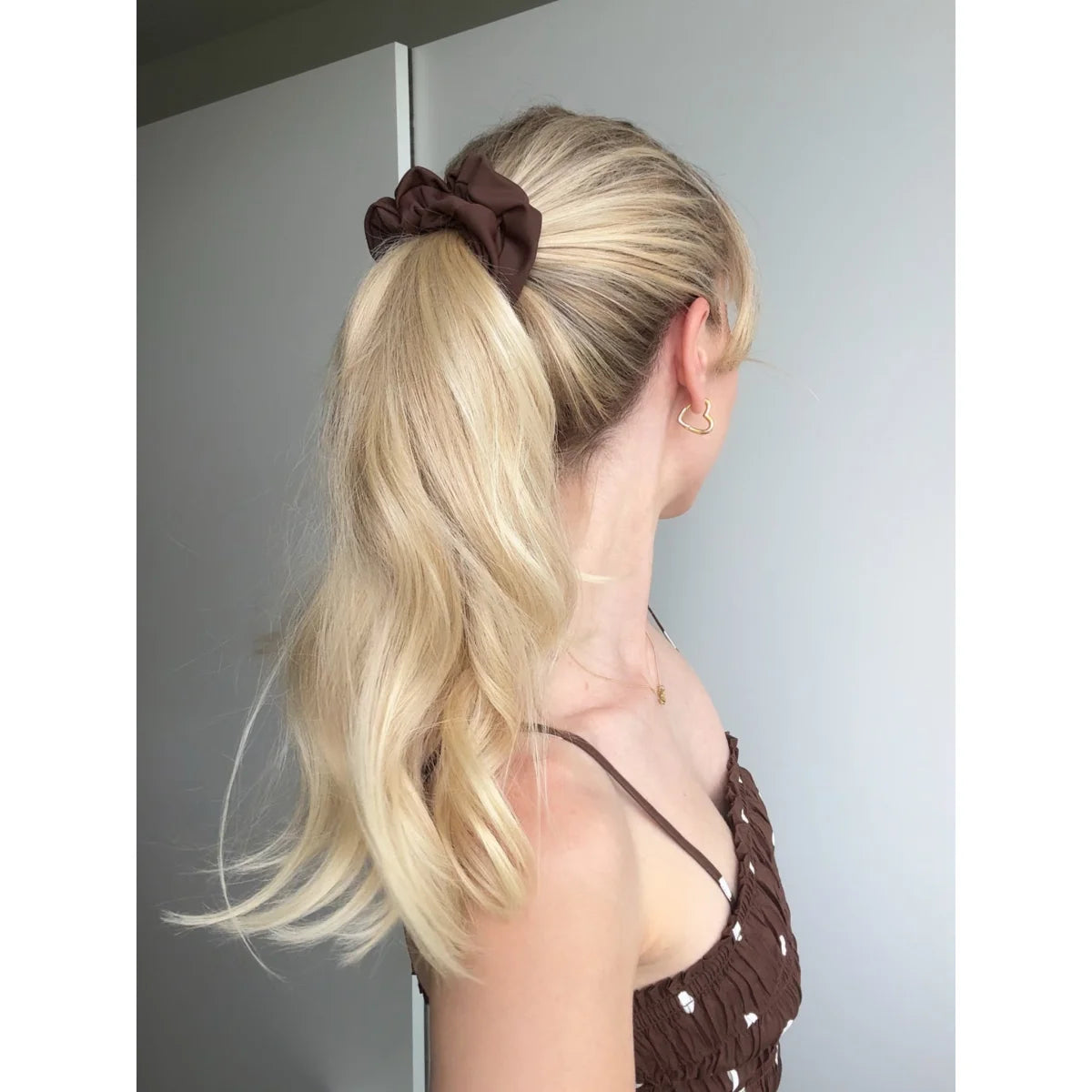 Mini mocha braunes stoff scrunchie hält blonde haare zu einem pferdeschwanz zusammen
