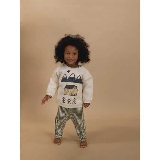 Lächelndes Kind trägt undyed Sweatshirt mit Cabin Adventure Grafik und gestreiften Hosen