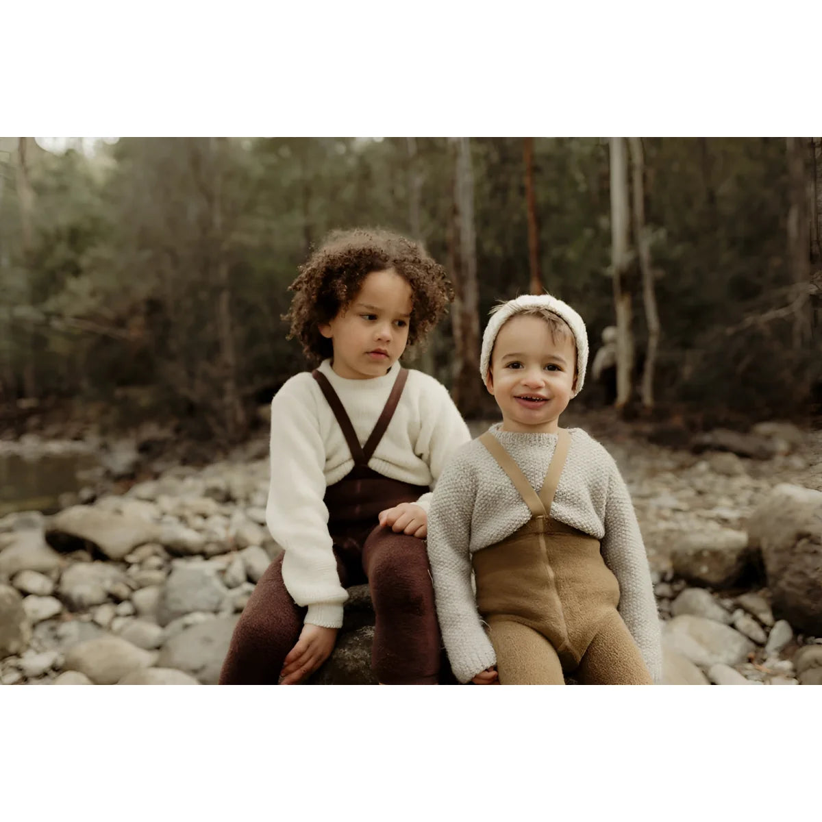 Zwei Kinder sitzen auf einem Felsen und tragen Teddy Warmy Strumpfhosen in Acorn Brown