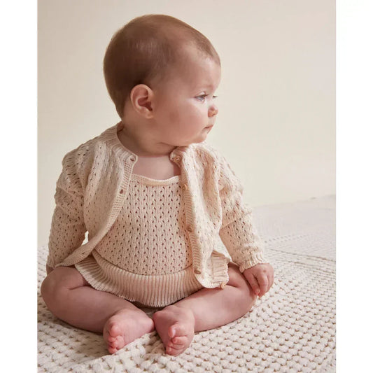 Baby im gestrickten Overall und Cardigan in zeitloser Kindermode für Fashionistas.