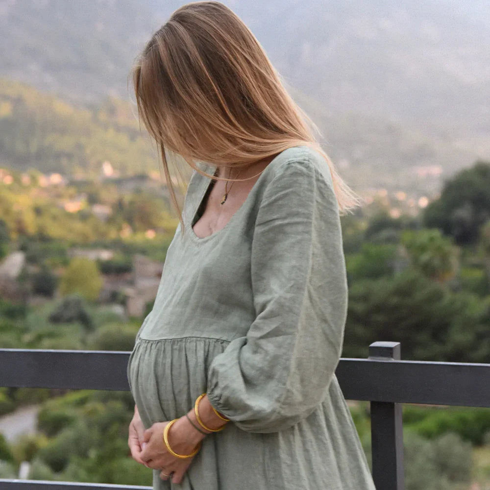 Schwangere Frau in langärmeligem salbeigrünem Kleid aus der Beachwood Kollektion.
