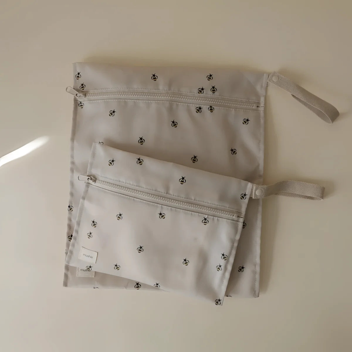 Set aus drei hellgrauen wet bags mit schwarzen bienenmotiven und stoffgriffen mit reißverschluss