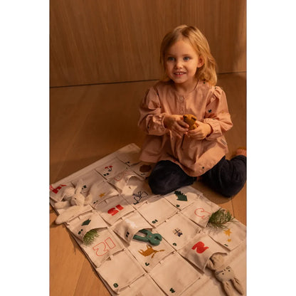 Lächelndes junges Mädchen hält kleines Objekt neben Adventskalender Holiday Sandy