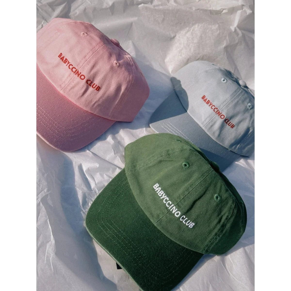 Drei babyccino club kids caps in rosa, blau und oliv mit nachhaltiger babykleidung schweiz und geschenken für neugeborene