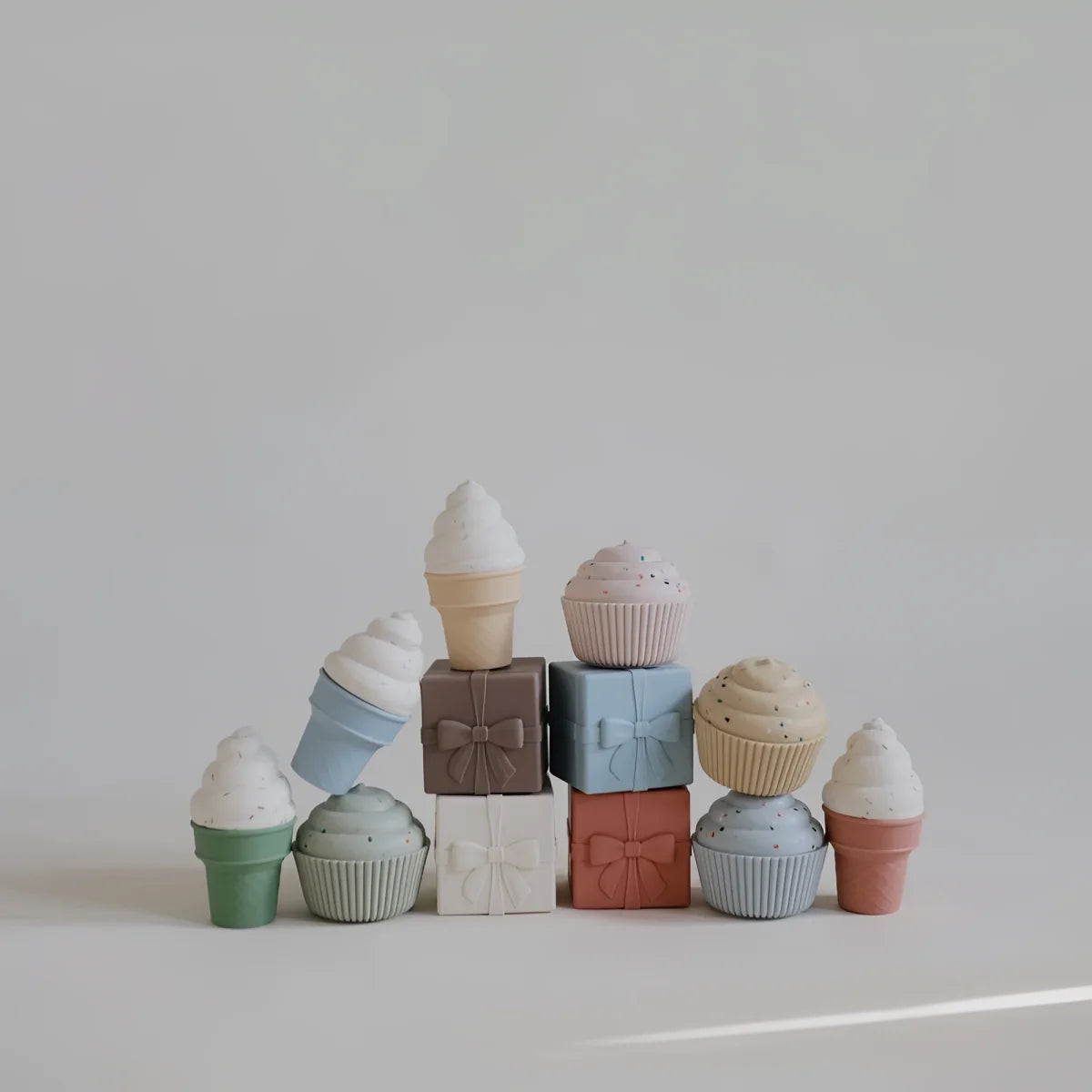 Pastellfarbene keramische badespielzeug-blöcke in eiscreme- und cupcake-form mit schleifen als dekorationsdetails