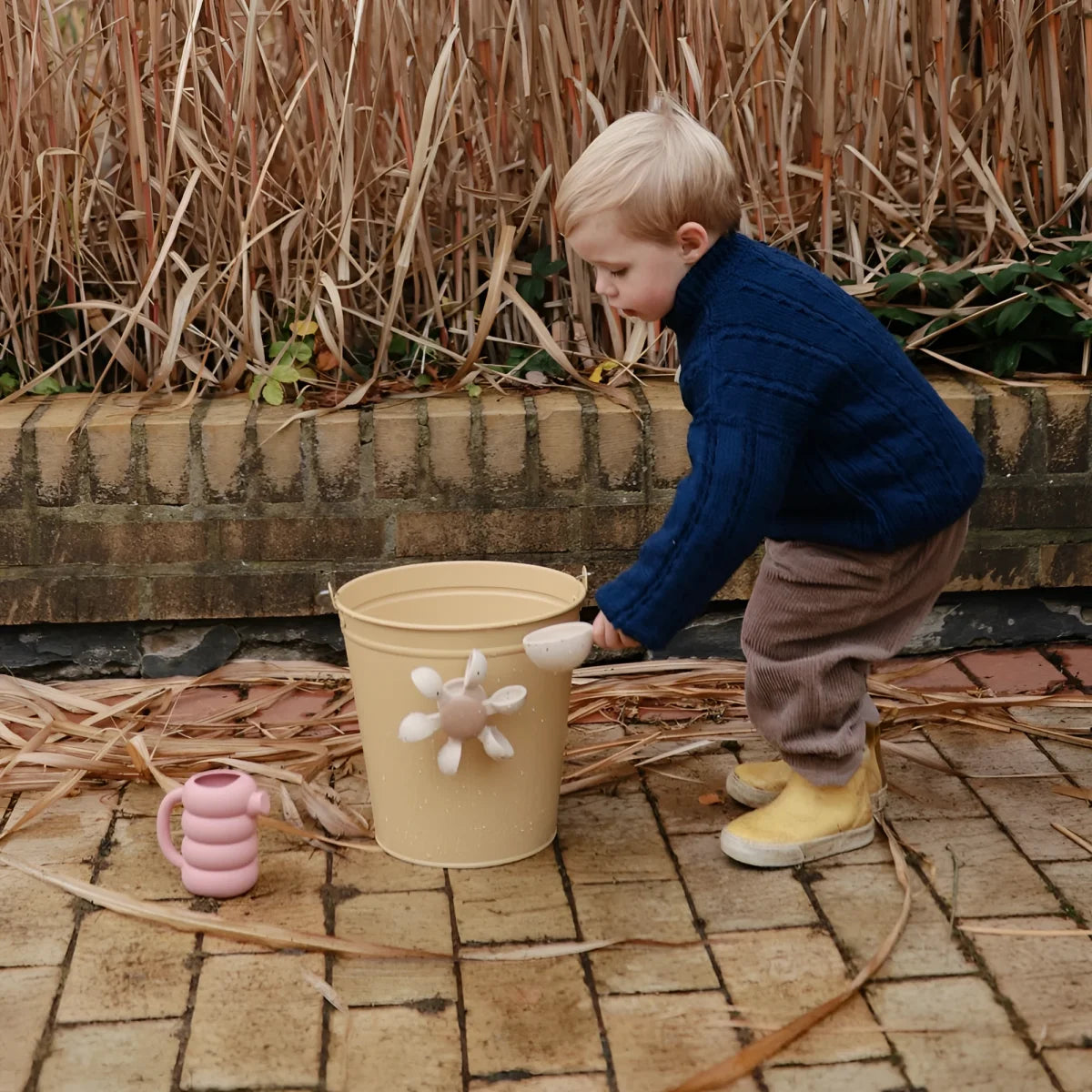 Beige metall gießkanne mit weißem blumenförmigem griffaufsatz für badespielzeug wasserrad