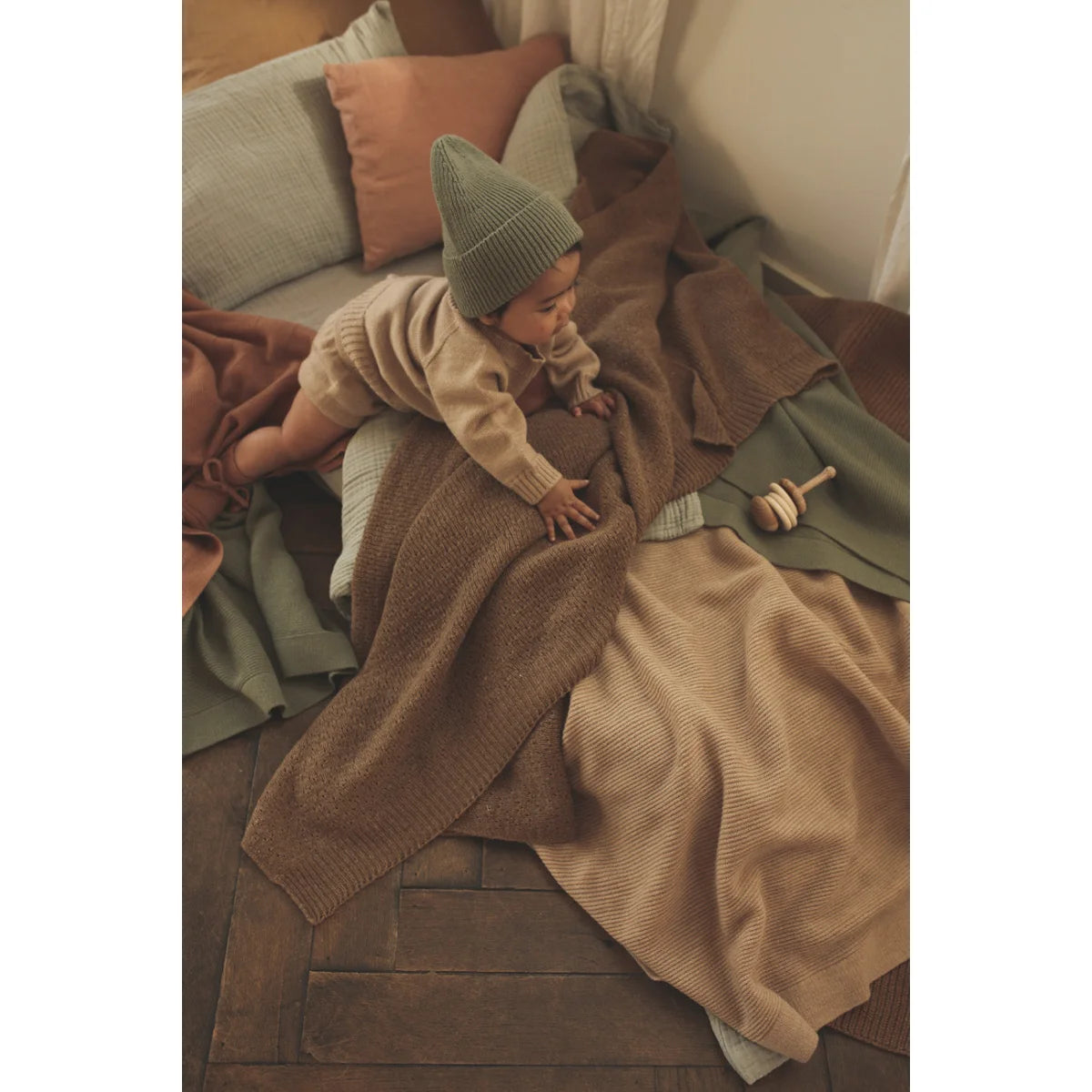 Baby in Beanie Fonzie Artichoke knit hat and sweater on cozy blankets