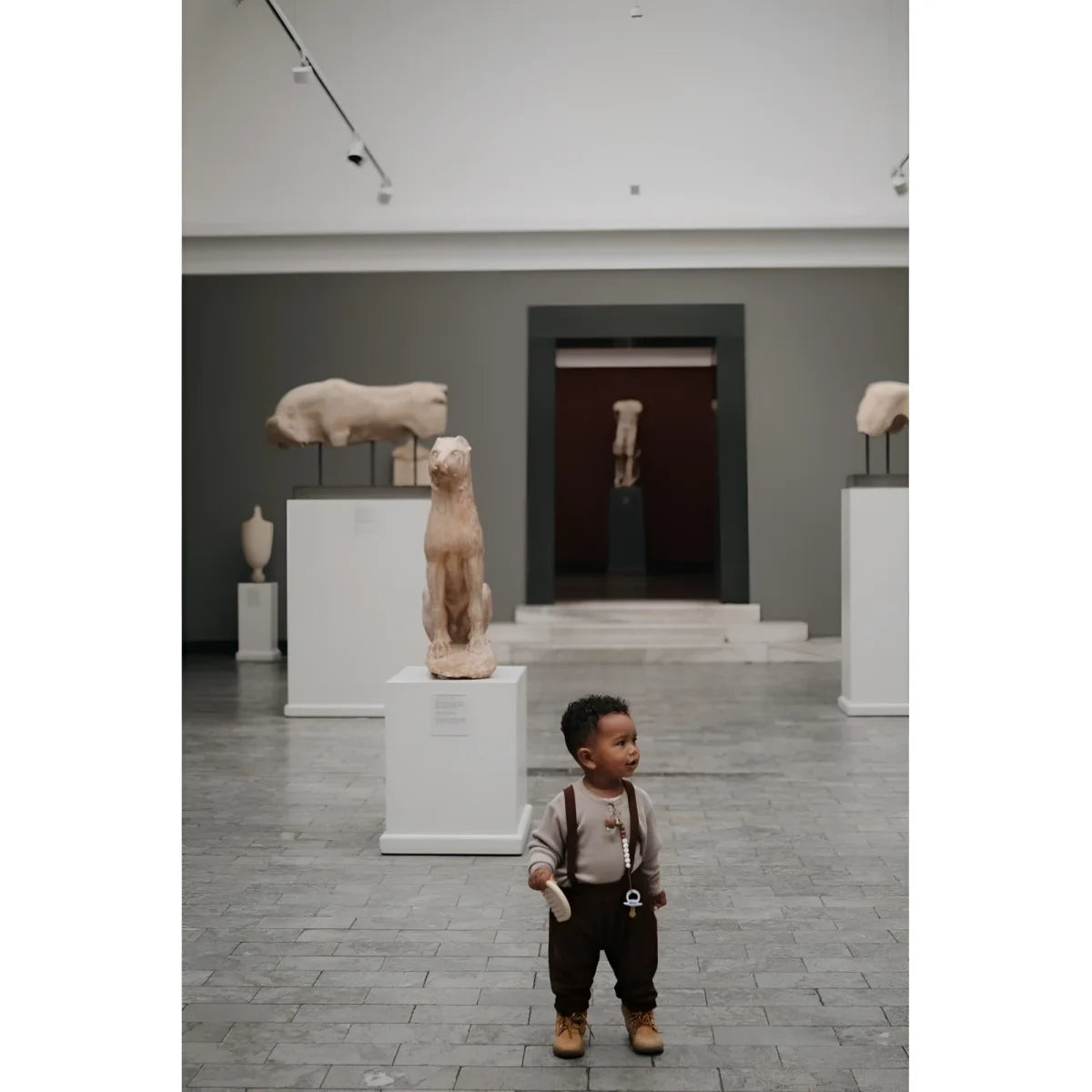 Junger Junge mit Hosenträgern und Shorts in einer Museumsgalerie
