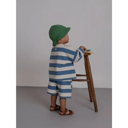 Eine frau und ein kind in passenden weißen outfits, das kind trägt bermudas mit deckchair-streifen in blau und weiß