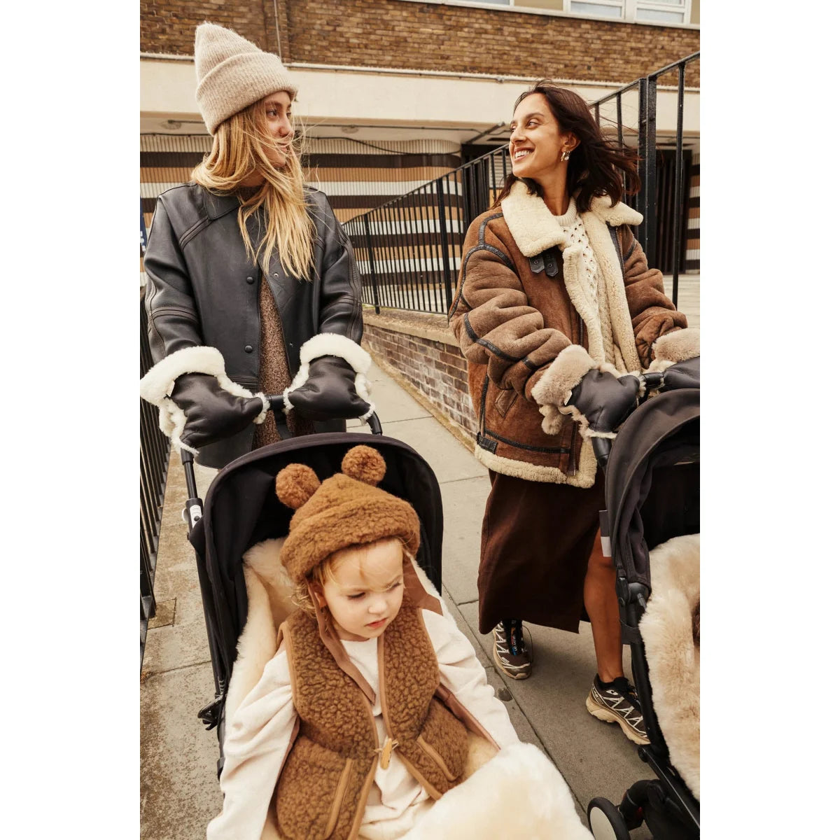 Drei Personen in Winterkleidung mit Kind im Kinderwagen und Beschichteten Kinderwagenhandschuhen