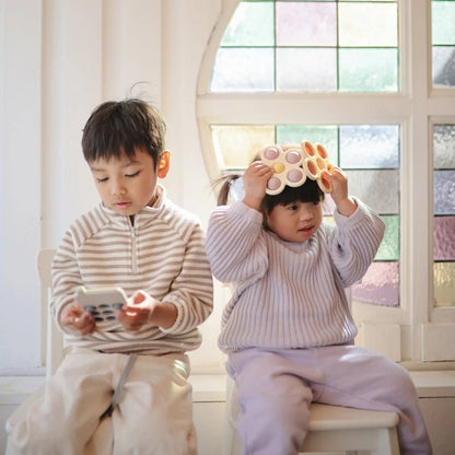 Zwei Kinder spielen mit Blume Plop-it Spielzeug in Lila und Gelb