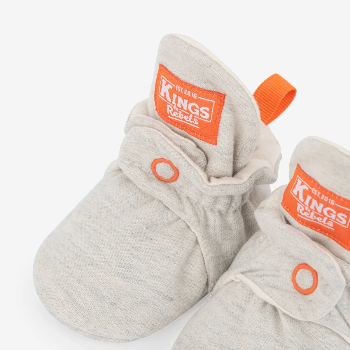 Graue strick-baby-booties aus baumwolle mit orangenem branding und zuglaschen nachhaltige babykleidung schweiz