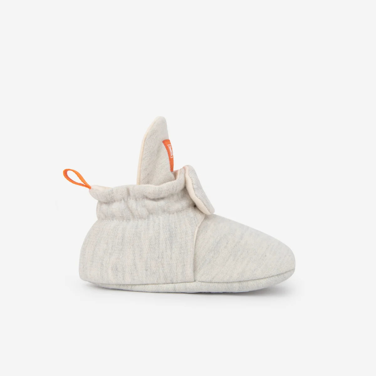 Weiche offwhite strick babybootie mit orangefarbener ziehschlaufe und markenlabel nachhaltige babykleidung schweiz