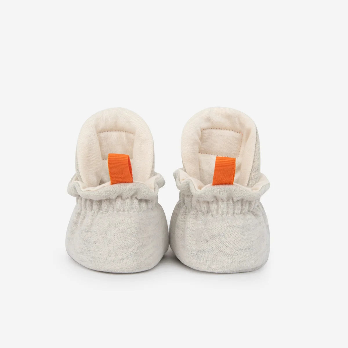 Weiche off-white babybooties aus baumwolle mit orangefarbenen ziehschlaufen für neugeborene geschenke nachhaltige