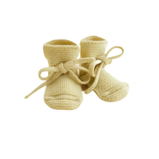 Ein Paar gestrickte Babyschuhe mit Schnürsenkeln in zartgelb