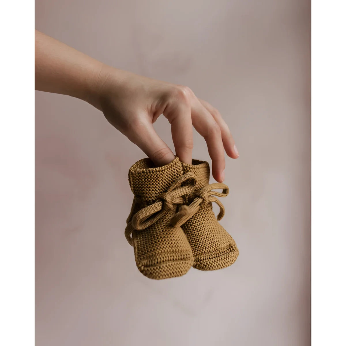 Paar gestrickte oder gehäkelte Babybooties in hellbrauner Farbe, Modell Ochre