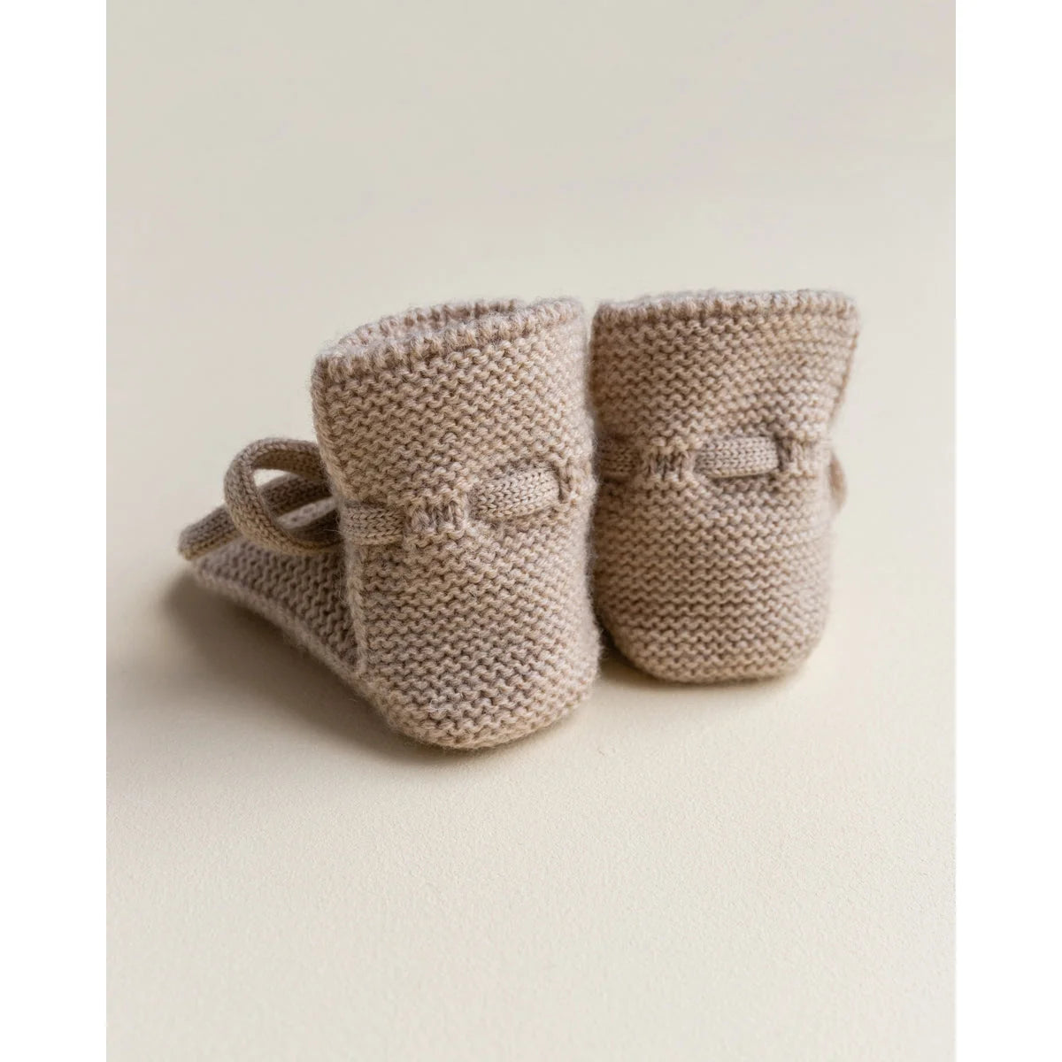 Beige gestrickte Babybooties mit kleinen Schleifen im Produktname Booties Sand
