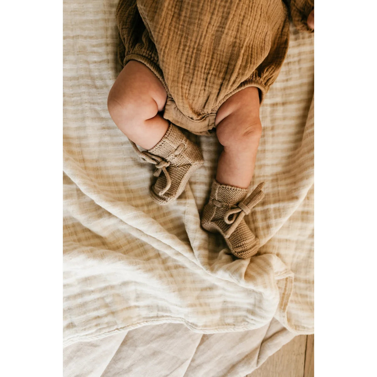Babylegs in gestrickten Sandbooties auf weichem Stoffuntergrund