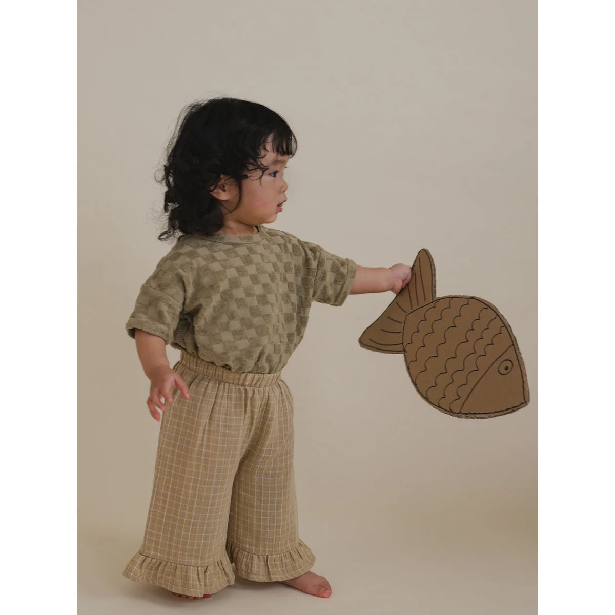 Kind hält einen Pappfisch in Verbindung mit Boxy T-Shirt aus Dusky Checkerboard Terry