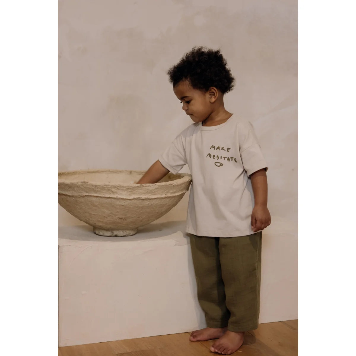Junger Junge steht neben einer Keramikschüssel auf einer Fläche mit Boxy T-Shirt