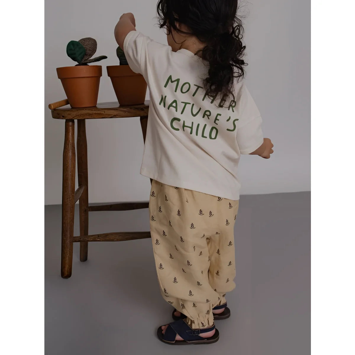 Rückseite Boxy T-Shirt Mother Natures Child: Kind in cremefarbenem Shirt mit dunkler Grün-Aufdruck