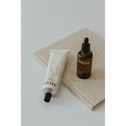 Skincare Produkte wie eine Tube und eine Glaspipette auf hellfarbener Stoffunterlage