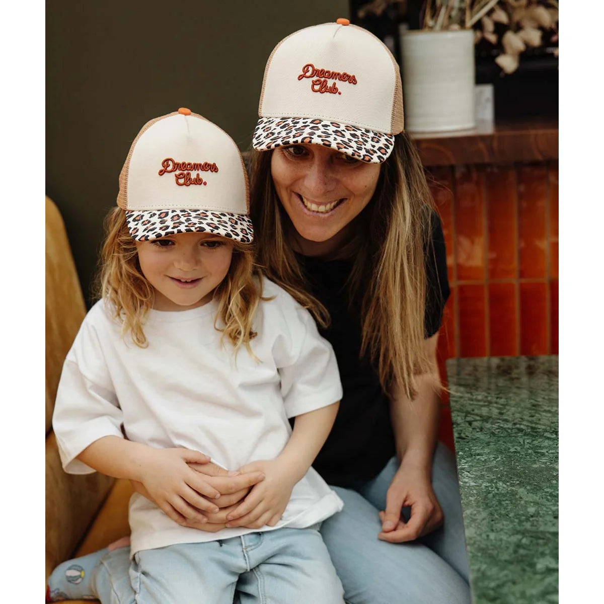Creamfarbene trucker cap mit leopardmuster-schirm und orange besticktem dreamers club logo