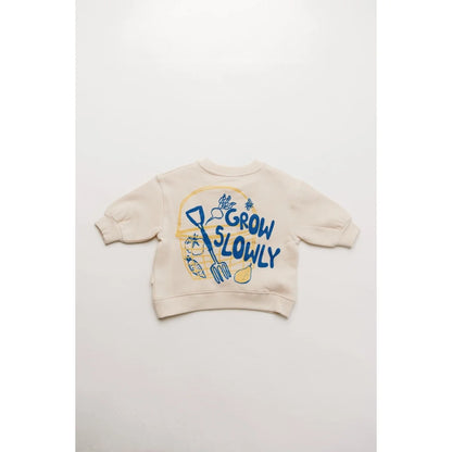 Creamfarbener Carner grow slowly Pullover für Kinder mit spielerischer grafik in blau und gelb mit gartengeräten und gemüse