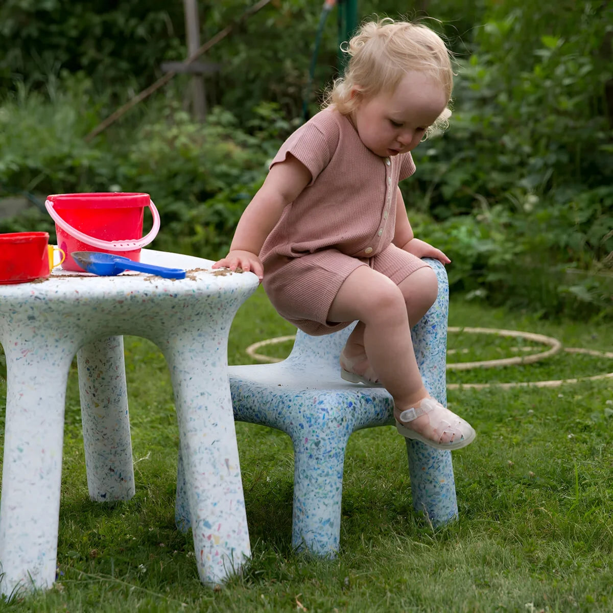 Ein toddler sitzt auf einem speckled blauen und weißen plastikstuhl charlie stuhl ocean im freien