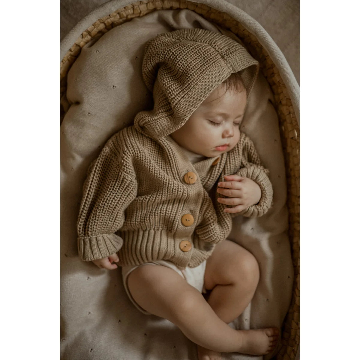 Schlafendes Baby in beiger Strickjacke und passendem Hut aus Chunky Knit Sand