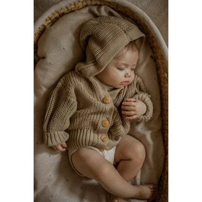 Schlafendes Baby in beiger Strickjacke und passendem Hut aus Chunky Knit Sand