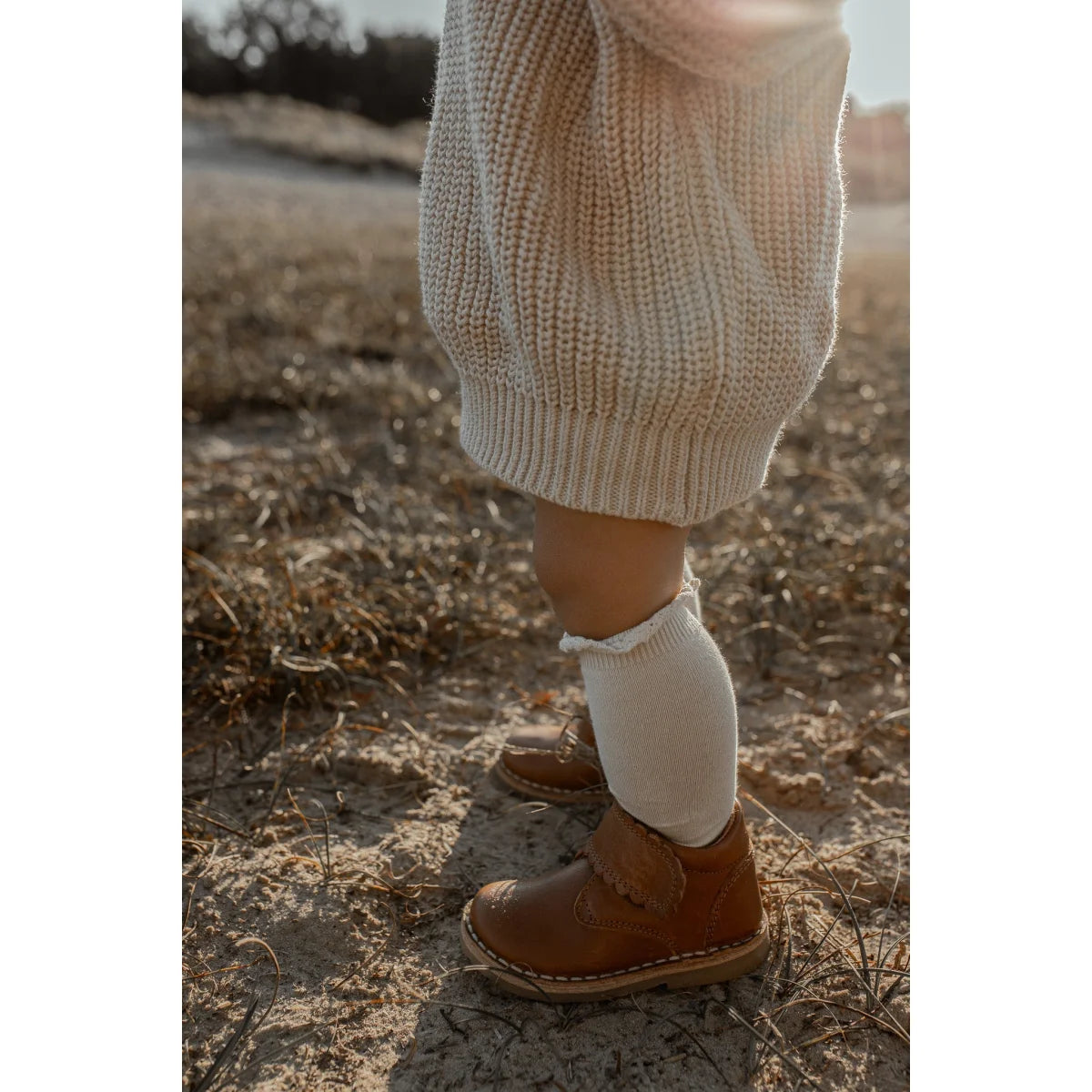 Braunes Leder-Ankle-Boot kombiniert mit weißer Socke und cremigem Pullover