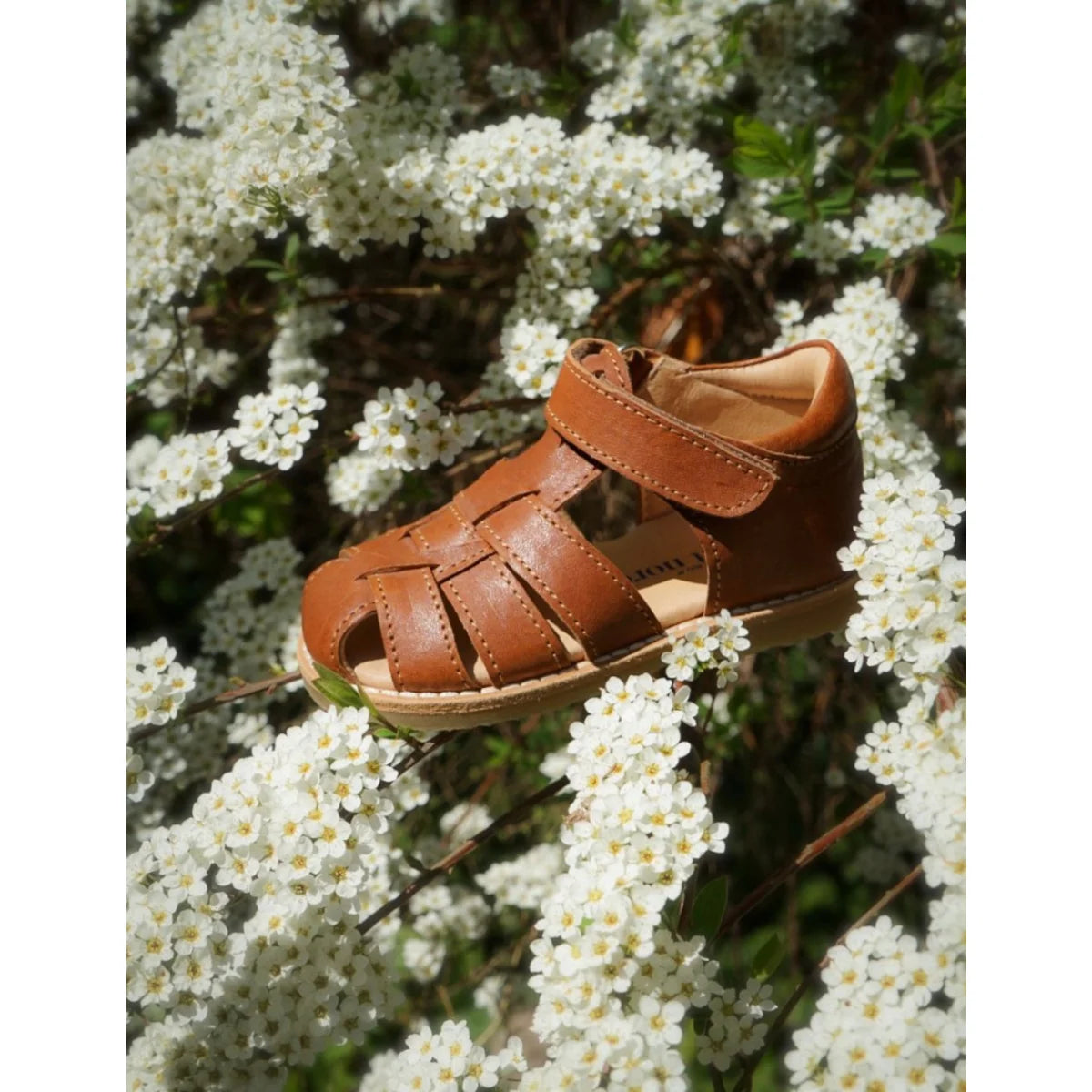Brauner leder-sandale mit gewebtem riemen und heller innenseite im stil klassischen sandal cognac