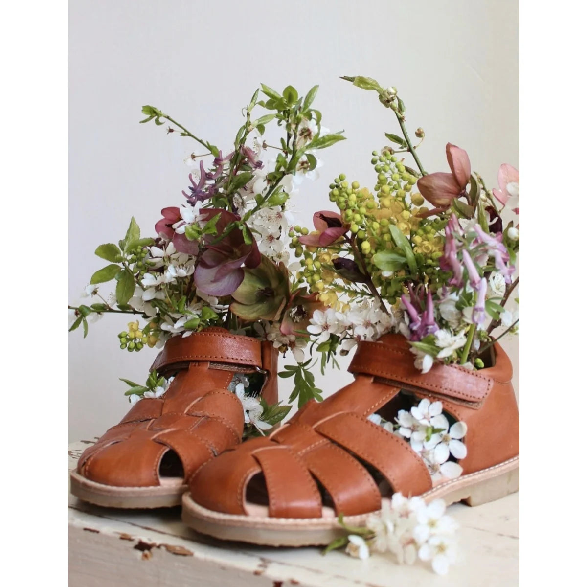 Klassische cognacfarbene sandalen aus braunem leder mit geflochtenen riemen und weicher sohle gefüllt mit weißen lila