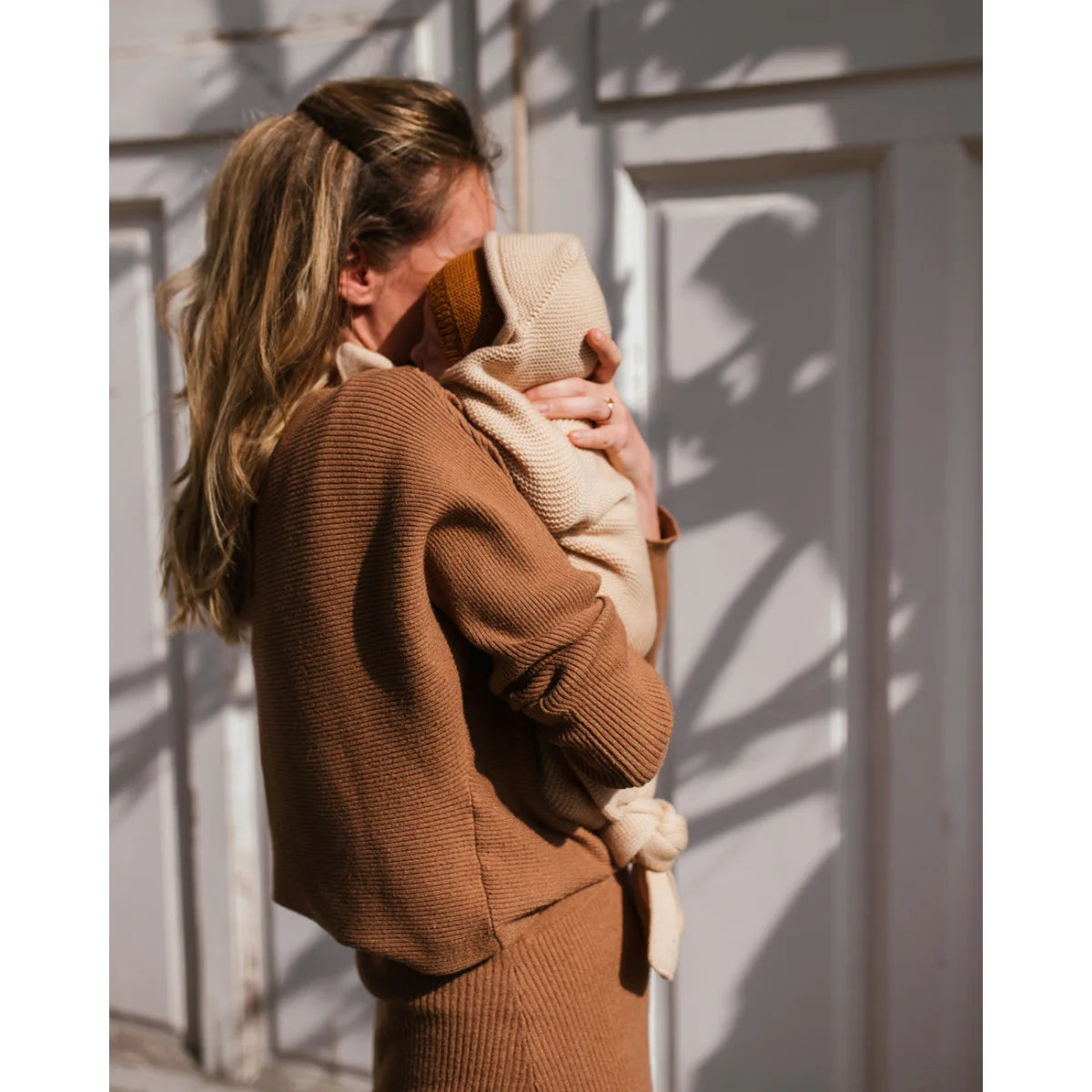 Frau hält Baby in der Sonne mit Cocoon Babydecke in Oat