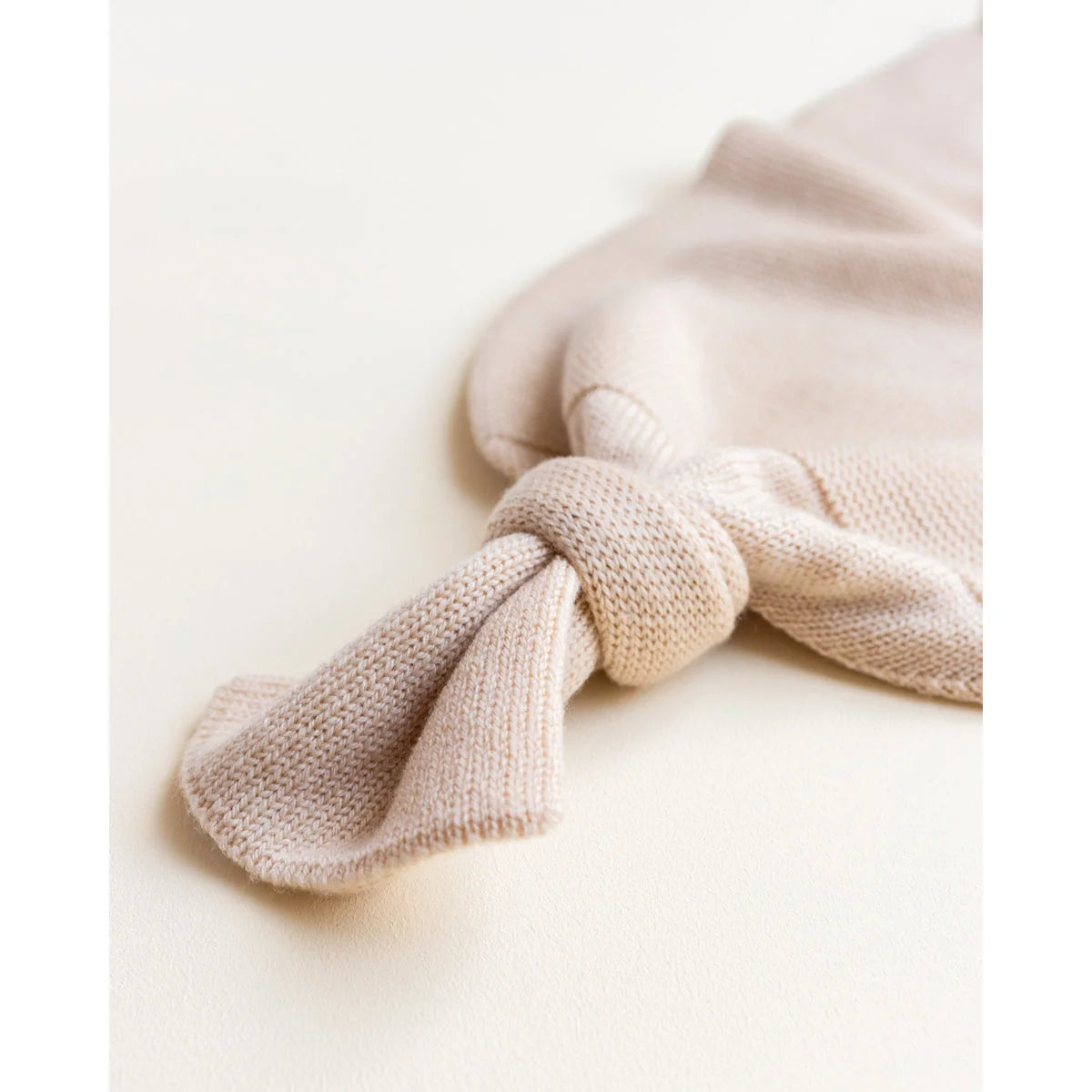 Weiches, gestricktes beiges Kaninchen-Spielzeug mit langen Ohren neben Cocoon Babydecke Oat