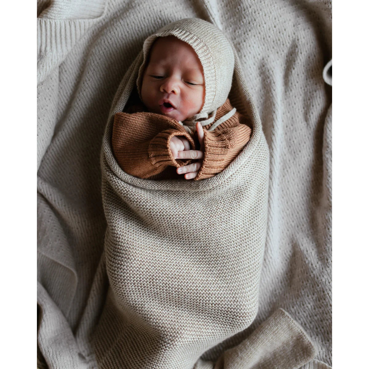 Neugeborenes Baby in einer gestrickten Decke mit einer Schleife um die Brust