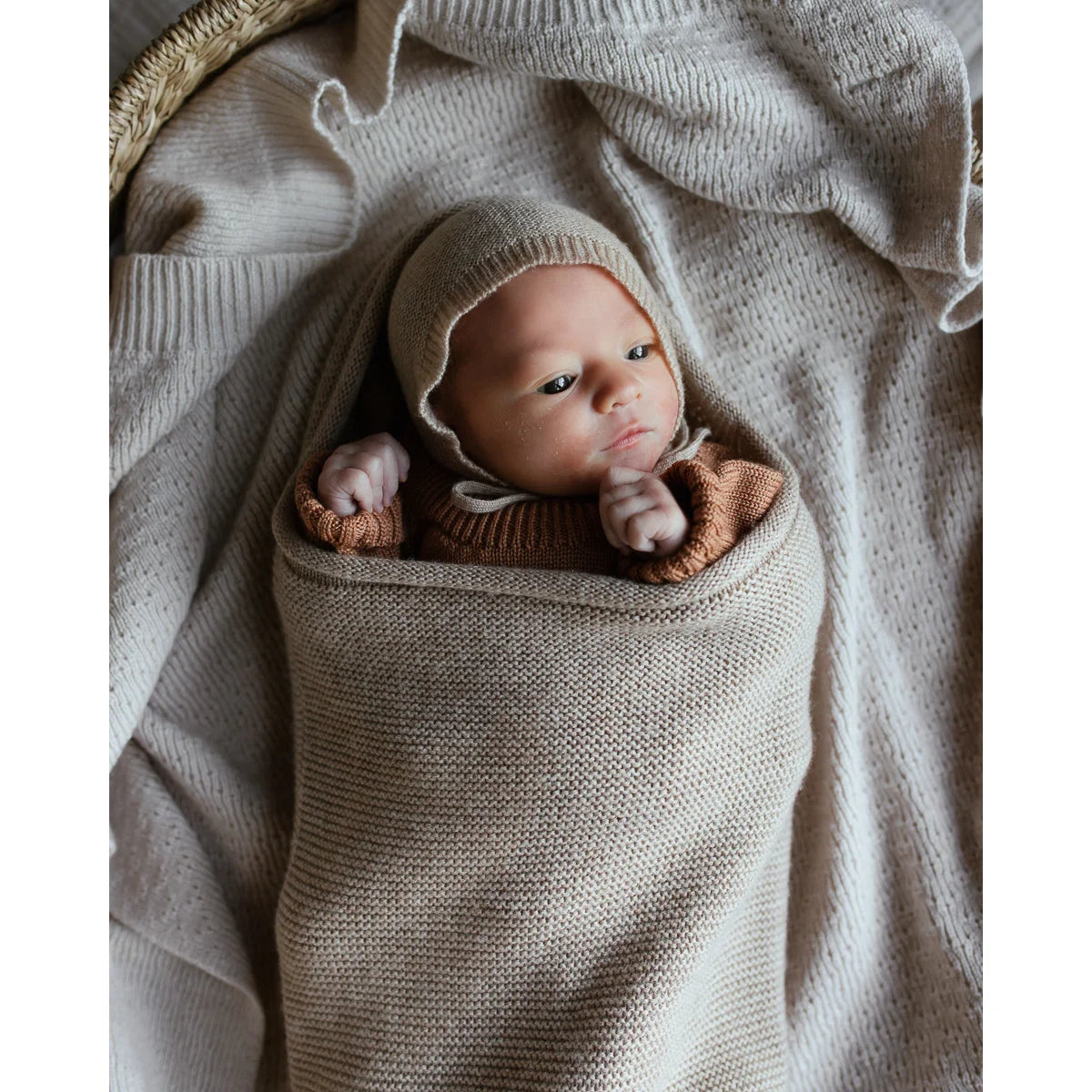 Neugeborenes Baby in einer gestrickten beigen Decke der Cocoon Babydecke | Sand